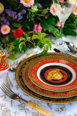 Güzel bir tabak ve mükemmel renkte çiçekler lüks bir masada duruyor.