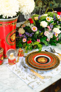 Güzel bir tabak ve mükemmel renkte çiçekler lüks bir masada duruyor.