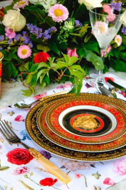 Güzel bir tabak ve mükemmel renkte çiçekler lüks bir masada duruyor.