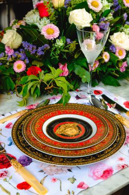 Güzel bir tabak ve mükemmel renkte çiçekler lüks bir masada duruyor.