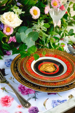 Güzel bir tabak ve mükemmel renkte çiçekler lüks bir masada duruyor.