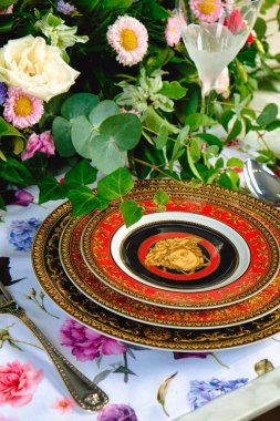 Güzel bir tabak ve mükemmel renkte çiçekler lüks bir masada duruyor.