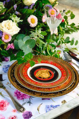 Güzel bir tabak ve mükemmel renkte çiçekler lüks bir masada duruyor.