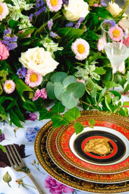 Güzel bir tabak ve mükemmel renkte çiçekler lüks bir masada duruyor.