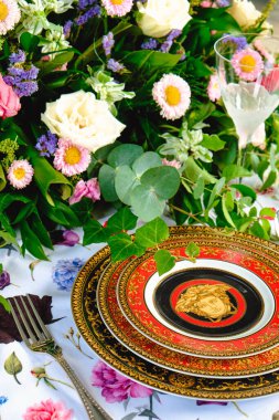 Güzel bir tabak ve mükemmel renkte çiçekler lüks bir masada duruyor.