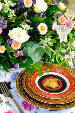 Güzel bir tabak ve mükemmel renkte çiçekler lüks bir masada duruyor.