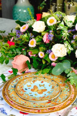Güzel bir tabak ve mükemmel renkte çiçekler lüks bir masada duruyor.