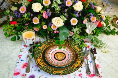 Güzel bir tabak ve mükemmel renkte çiçekler lüks bir masada duruyor.