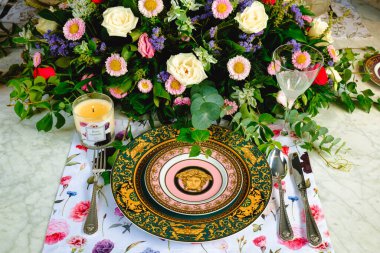 Güzel bir tabak ve mükemmel renkte çiçekler lüks bir masada duruyor.