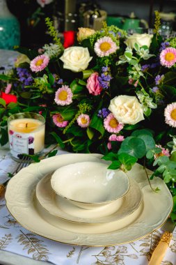 Güzel bir tabak ve mükemmel renkte çiçekler lüks bir masada duruyor.