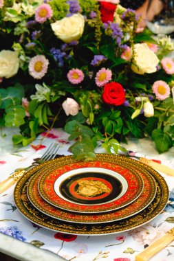 Güzel bir tabak ve mükemmel renkte çiçekler lüks bir masada duruyor.