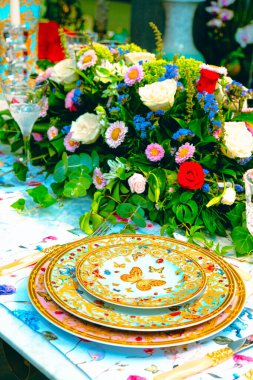 Güzel bir tabak ve mükemmel renkte çiçekler lüks bir masada duruyor.