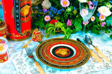 Güzel bir tabak ve mükemmel renkte çiçekler lüks bir masada duruyor.