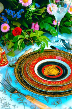 Güzel bir tabak ve mükemmel renkte çiçekler lüks bir masada duruyor.