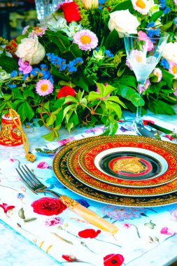 Güzel bir tabak ve mükemmel renkte çiçekler lüks bir masada duruyor.