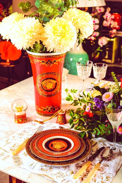 Güzel bir tabak ve mükemmel renkte çiçekler lüks bir masada duruyor.