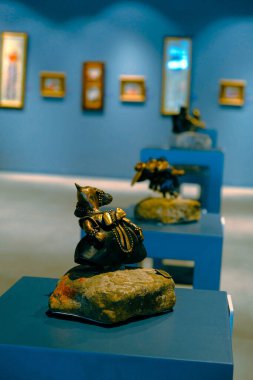 Kadın sergideki eserlere ve sergideki eserlere bakıyor.