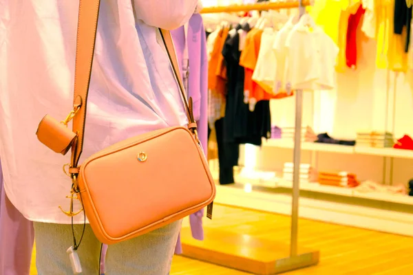 a woman wearing a bag in the store and holding the bag in her hands