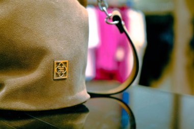 Dükkanda çanta takan ve elinde çanta tutan bir kadın.