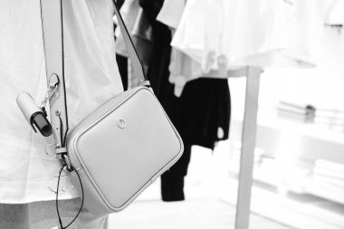 Dükkanda çanta takan ve elinde çanta tutan bir kadın.