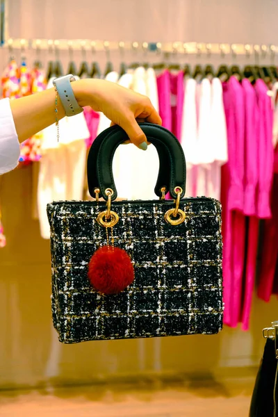 a woman wearing a bag in the store and holding the bag in her hands