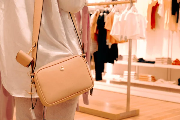 a woman wearing a bag in the store and holding the bag in her hands