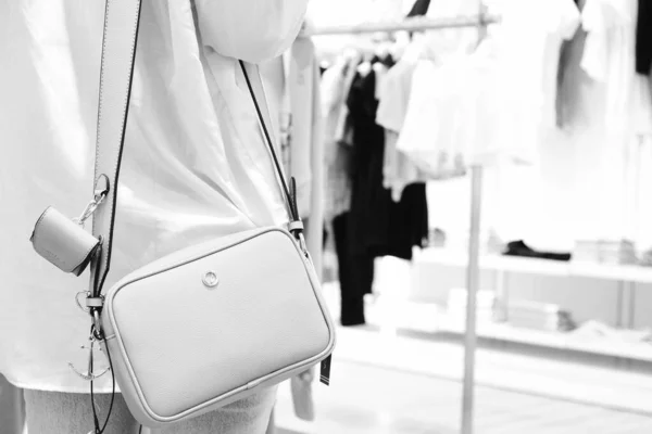 a woman wearing a bag in the store and holding the bag in her hands