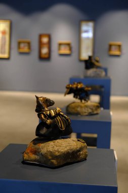 Kadın sergideki eserlere ve sergideki eserlere bakıyor.