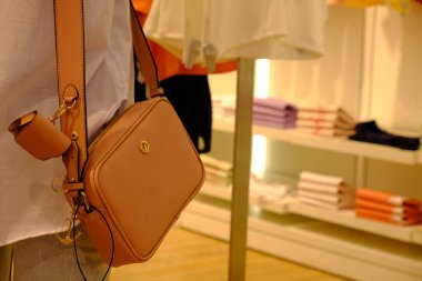 Dükkanda çanta takan ve elinde çanta tutan bir kadın.