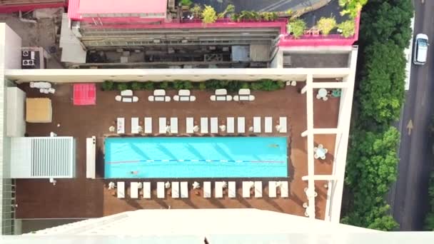 Vista aérea de la piscina de la azotea con gente y tumbonas alrededor. Relajarse y nadar en un entorno urbano — Vídeo de stock