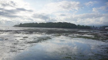 Deniz suyuna yansıyan güneş ışınları ile güzel mavi gökyüzü kumsal manzarası