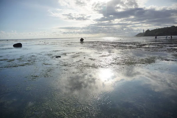 Deniz suyuna yansıyan güneş ışınları ile güzel mavi gökyüzü kumsal manzarası