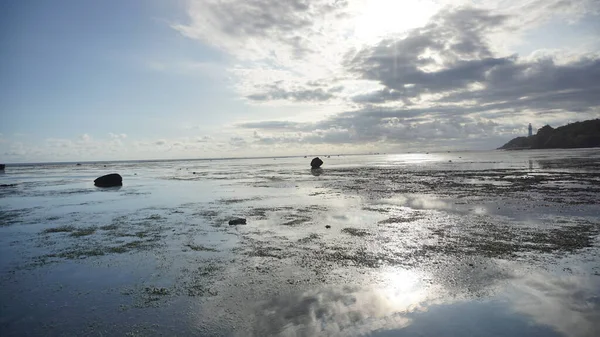 Deniz suyuna yansıyan güneş ışınları ile güzel mavi gökyüzü kumsal manzarası