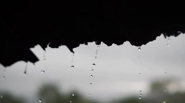 Çatıdan düşen yağmur damlaları bembeyaz görünüyor.