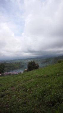 beautiful vertical video portrait beautiful mountain natural scenery hilly nature panorama, with forest of tall green trees and green slopes under cloudy blue sky in daytime