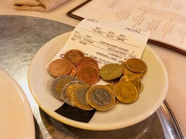 Madrid, İspanya; 06 01 2017. Nakit bilet ve euro sikkeleriyle ödeme. Bir restoran faturası garson tarafından ödenmeyi bekliyor..