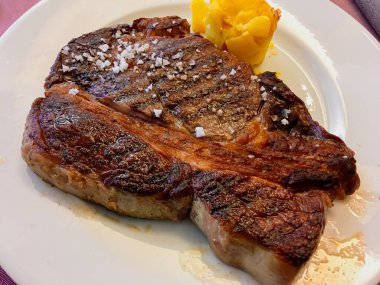 Biftek ızgara ve yenmeye hazır. Lezzetli ve lezzetli bir et yemeği güzel pişmiş patates ve kaba tuzla sunulur..