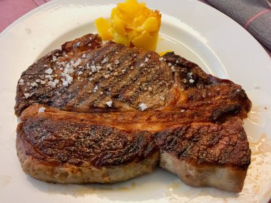 Biftek ızgara ve yenmeye hazır. Lezzetli ve lezzetli bir et yemeği güzel pişmiş patates ve kaba tuzla sunulur..