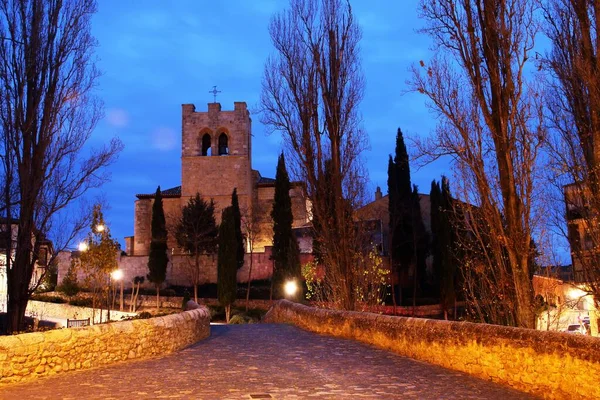 日落在圣胡安天主教教堂和西班牙布尔戈斯Aranda Duero的中世纪桥上 夕阳西下的蓝天 没有树叶的树 灯街照亮了整个场景 — 图库照片