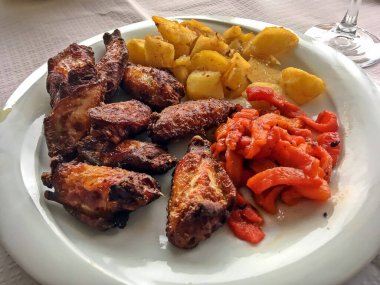 Kızarmış patates ve biberli ızgara tavuk kanadı. İspanyol yemeği. Tabak bir restoranda servis edildi ve yemeye hazır..