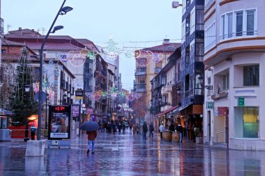 Soria, İspanya; 12 09 2017. Noel ışıkları süslemeli Marques Vadillo Caddesi. Yağmurlu bir akşamda insanlar Central Street 'te geziniyor..