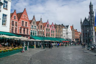 Bruges, Belçika; 04 28 2016. Bruges 'deki Pazar Meydanı. Meydandaki geleneksel ortaçağ binalarının cephelerinin yanındaki restoran ve kafelerin terasları..