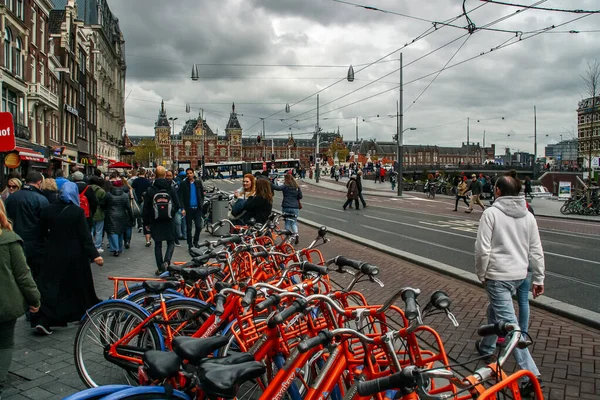 Amsterdam, Hollanda; 04: 30 2016. Damrak Bulvarı ve Centraal İstasyonu (İngilizce: Amsterdam Central Station) Kraliçe 'nin zamanında. Amsterdam birçok bisikletiyle şehir manzarası.