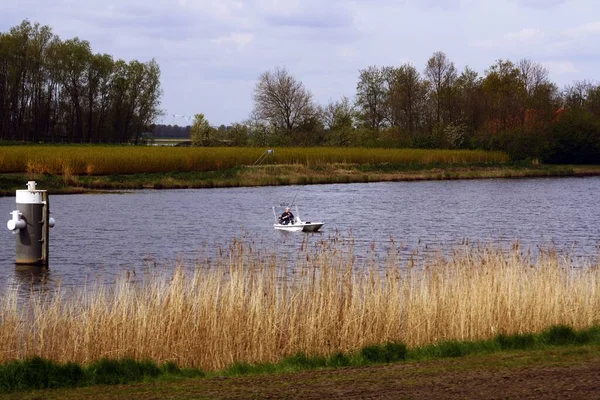 彼の小さなボートから釣りをスポーツ漁師 オランダの多くの運河の一つで漁師が畑に囲まれています — ストック写真