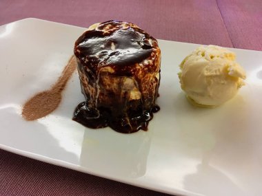 Lezzetli bir tatlı, üç çikolatalı pasta ve bir kepçe vanilyalı dondurma. Kaşık şeklinde esmer şekerle süslenmiş tabak..