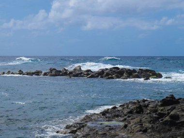 İspanya 'nın Gran Canaria Adası' ndaki El Puertillo kasabasının kıyı manzarası. Volkanik kayalıklardaki dalgaların oluşturduğu engebeli bir manzara..