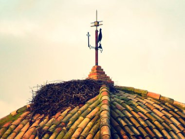 Santa Cruz de Paymogo inzivasında leylek yuvası olan çatı. Paymogo, Huelva, İspanya yakınlarındaki Katolik dini binası. Fotoğraf gün batımında çekildi..