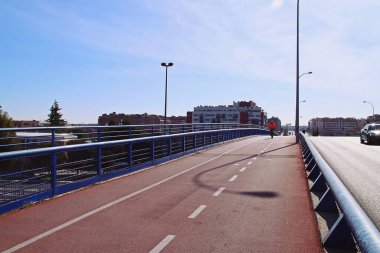 Güneşli bir kış sabahında bisikletçi spor yapıyor. Madrid, İspanya 'daki A1 otoyolunun üzerindeki Niceto Alcala Zamora bulvarı köprüsünde bisiklet yolu.