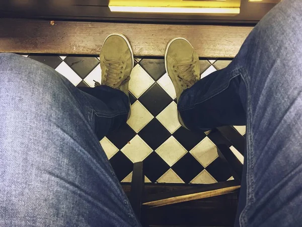 Green sneakers and blue jeans from the photographer\'s view. Perspective that is observed in the first person when one is seated.