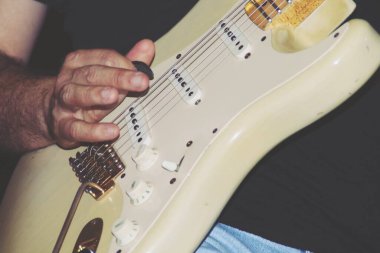 Bir gösteride elektro gitar çalmak. Elektro gitarın tellerinde tırnağı olan el..